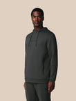 Man wearing a dark gray hoodie and pants on a beige background