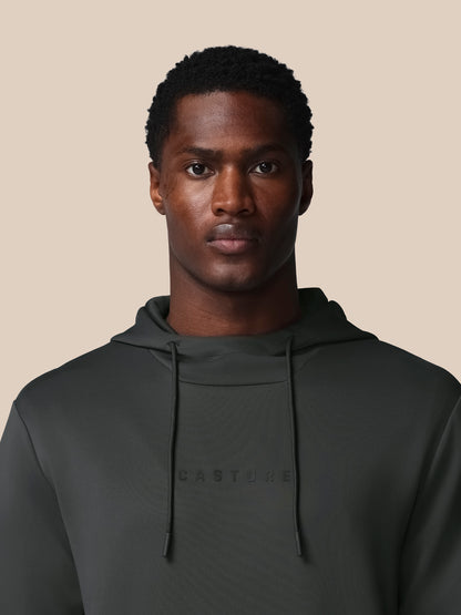 Man wearing a dark green hoodie with 'CASTORE' branding on a beige background