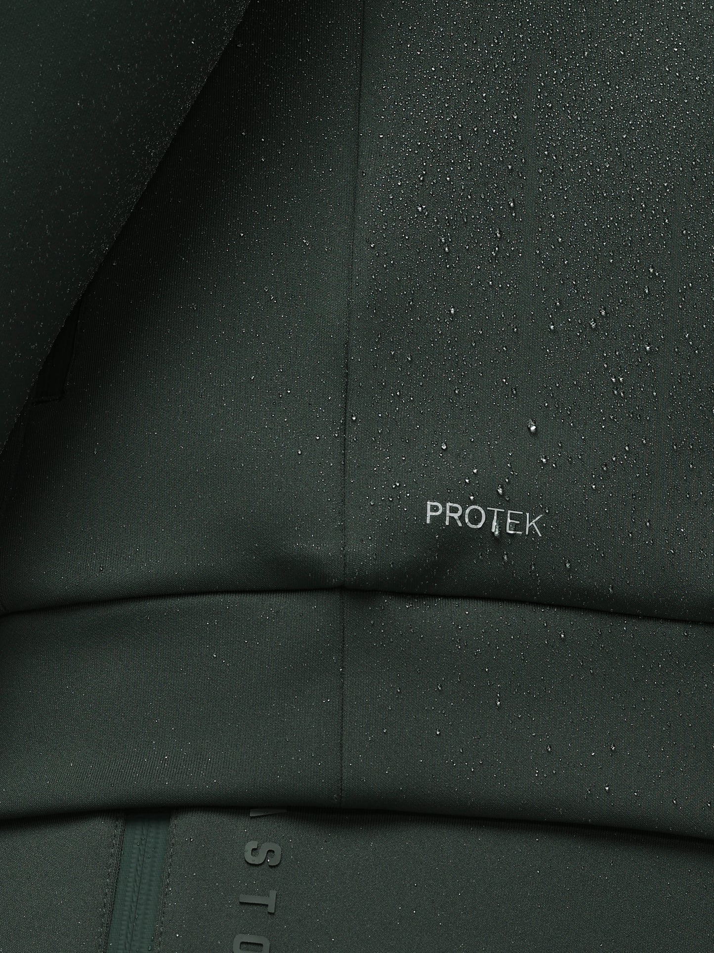 Close-up of a dark green fabric with 'PROTEK' branding, showing water droplets.