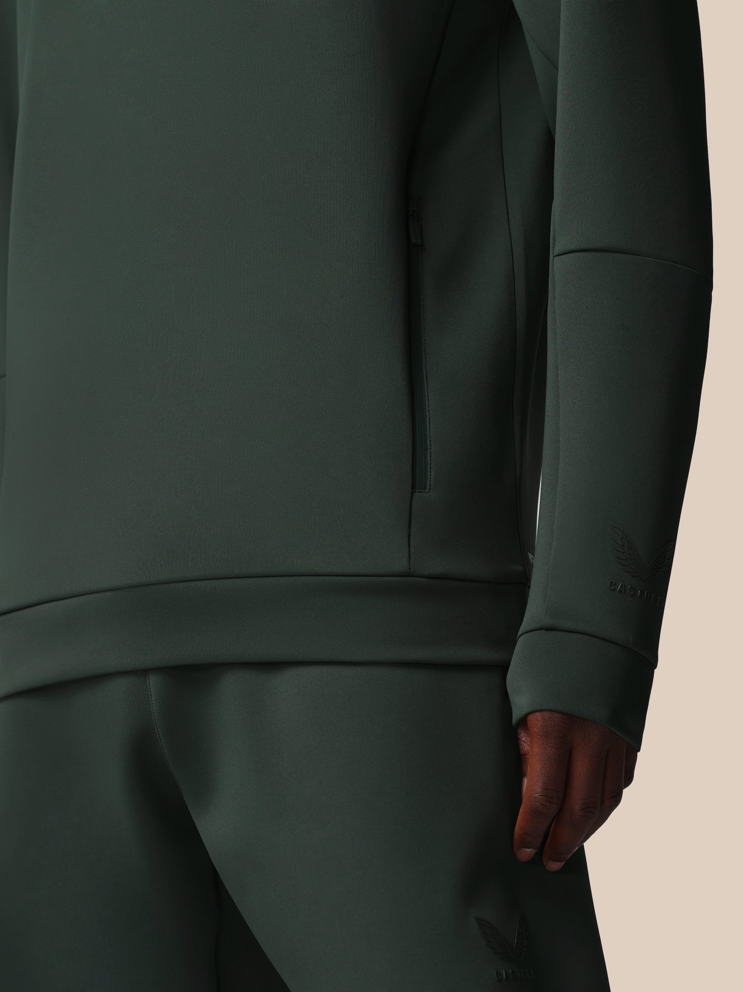 Dark green outfit with a close-up of the sleeve on a beige background