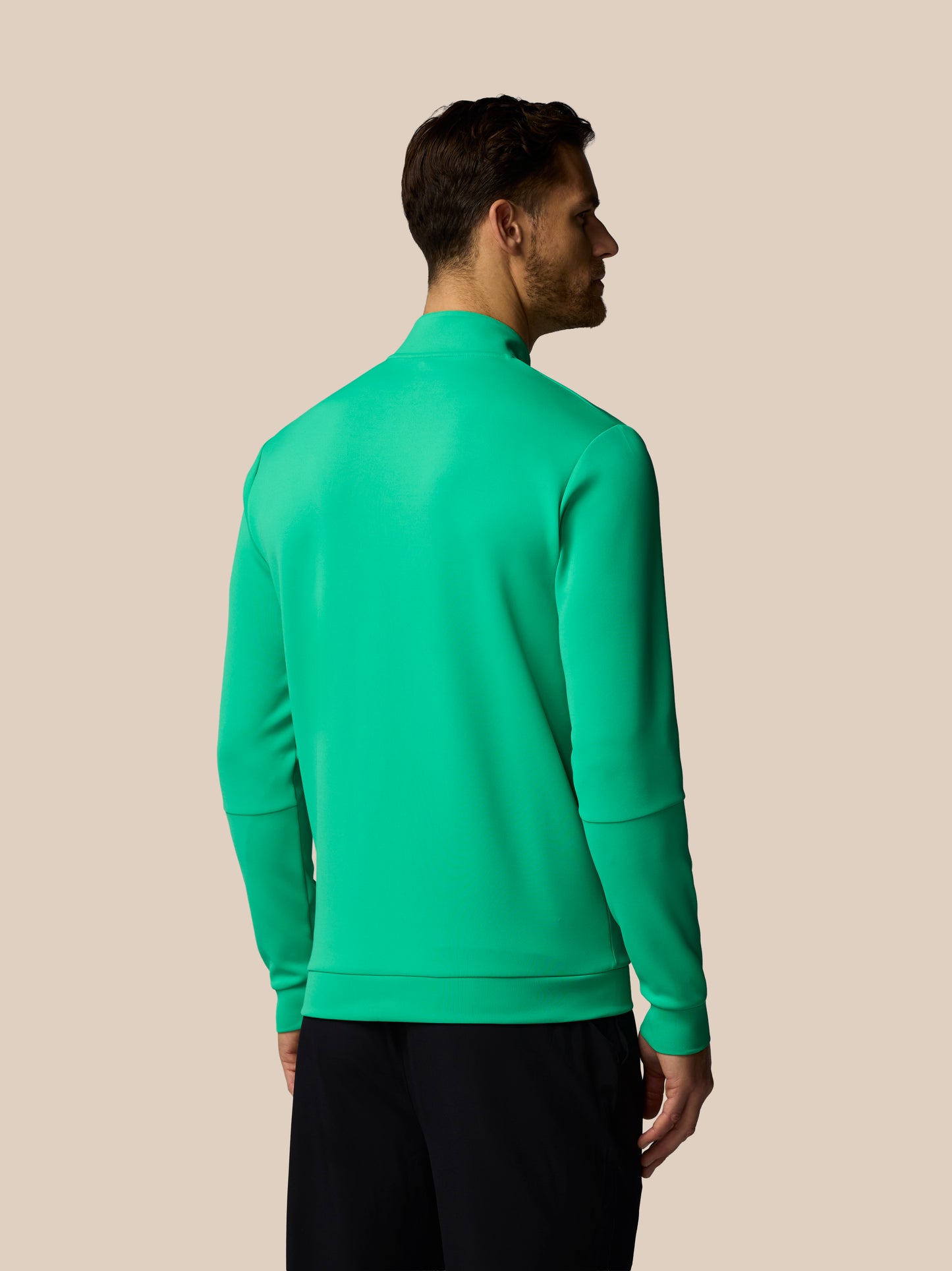 Man wearing a green quarter-zip sweatshirt on a beige background
