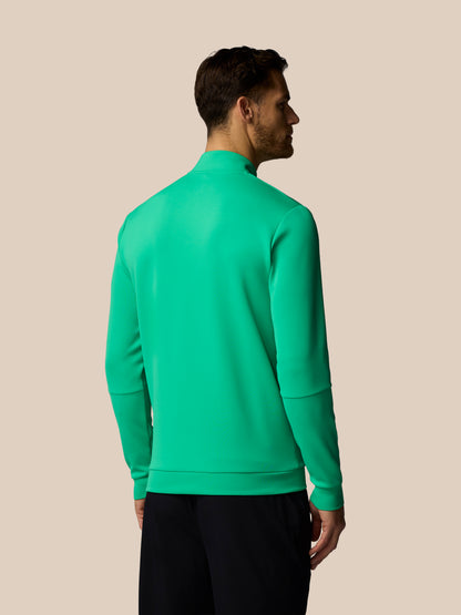 Man wearing a green quarter-zip sweatshirt on a beige background
