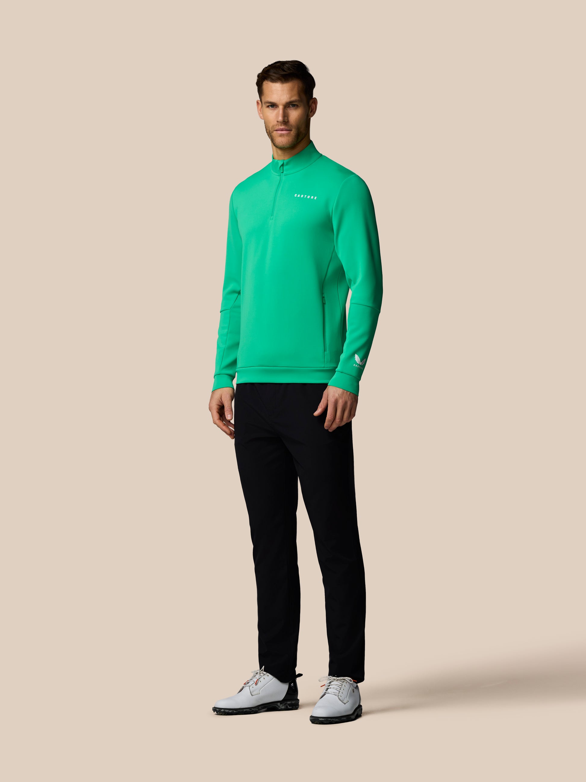 Man wearing a green long-sleeve shirt and black pants on a beige background