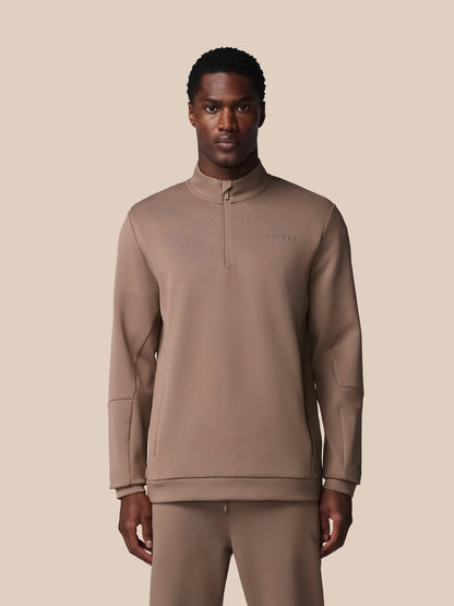 Man wearing a brown tracksuit against a beige background