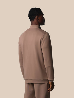 Man wearing a beige tracksuit against a plain background
