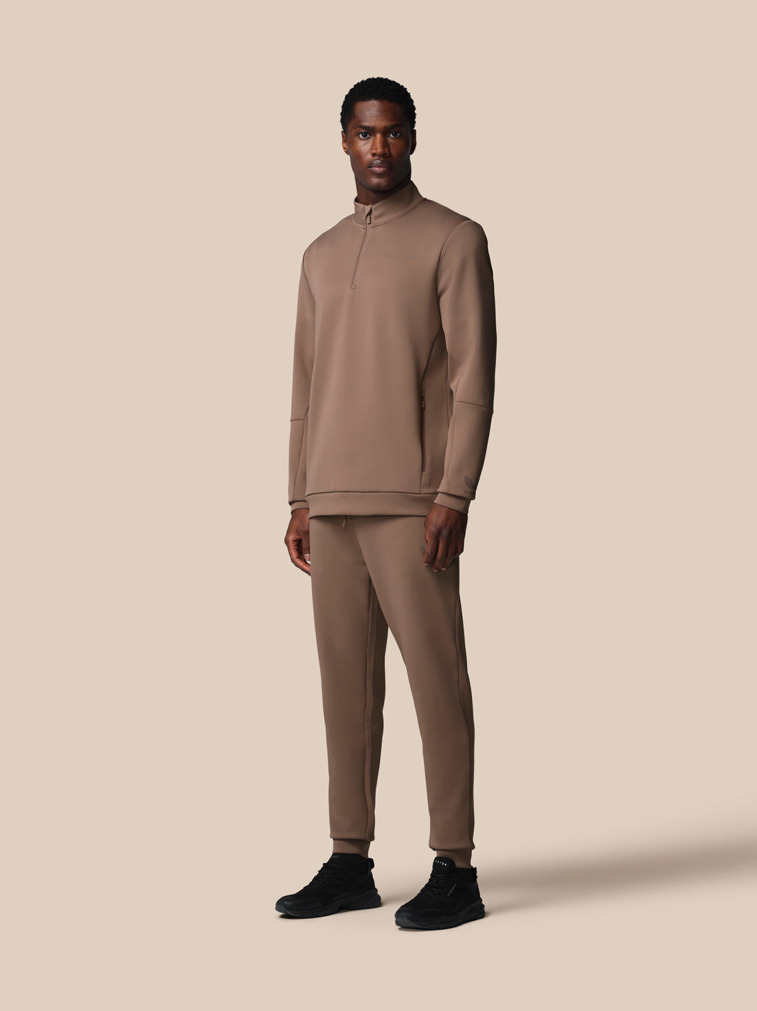 Man wearing a beige tracksuit on a beige background