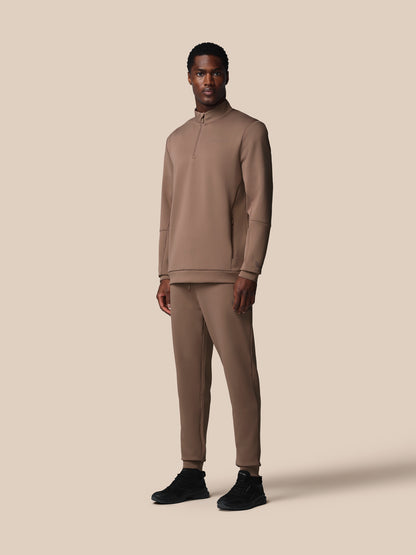 Man wearing a beige tracksuit on a beige background