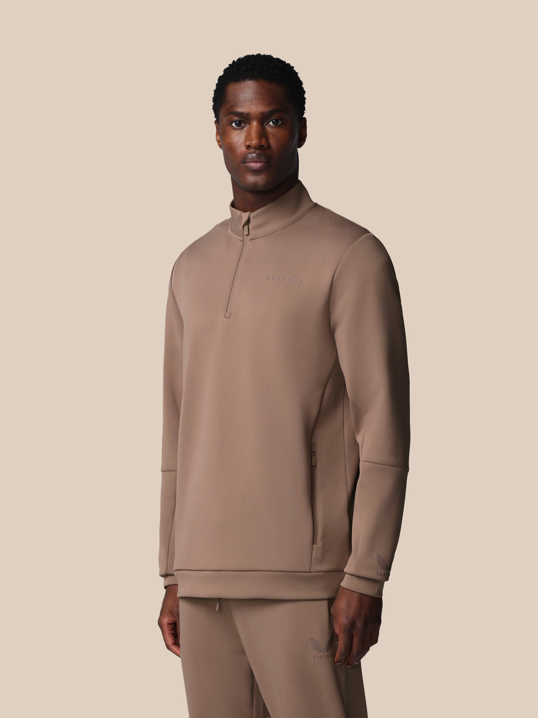 Man wearing a beige long-sleeve shirt and pants on a beige background