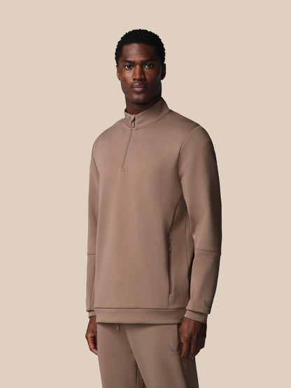 Man wearing a beige long-sleeve shirt and pants on a beige background