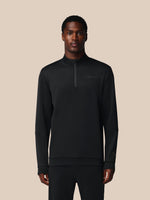 Man wearing a black quarter-zip sweatshirt on a beige background