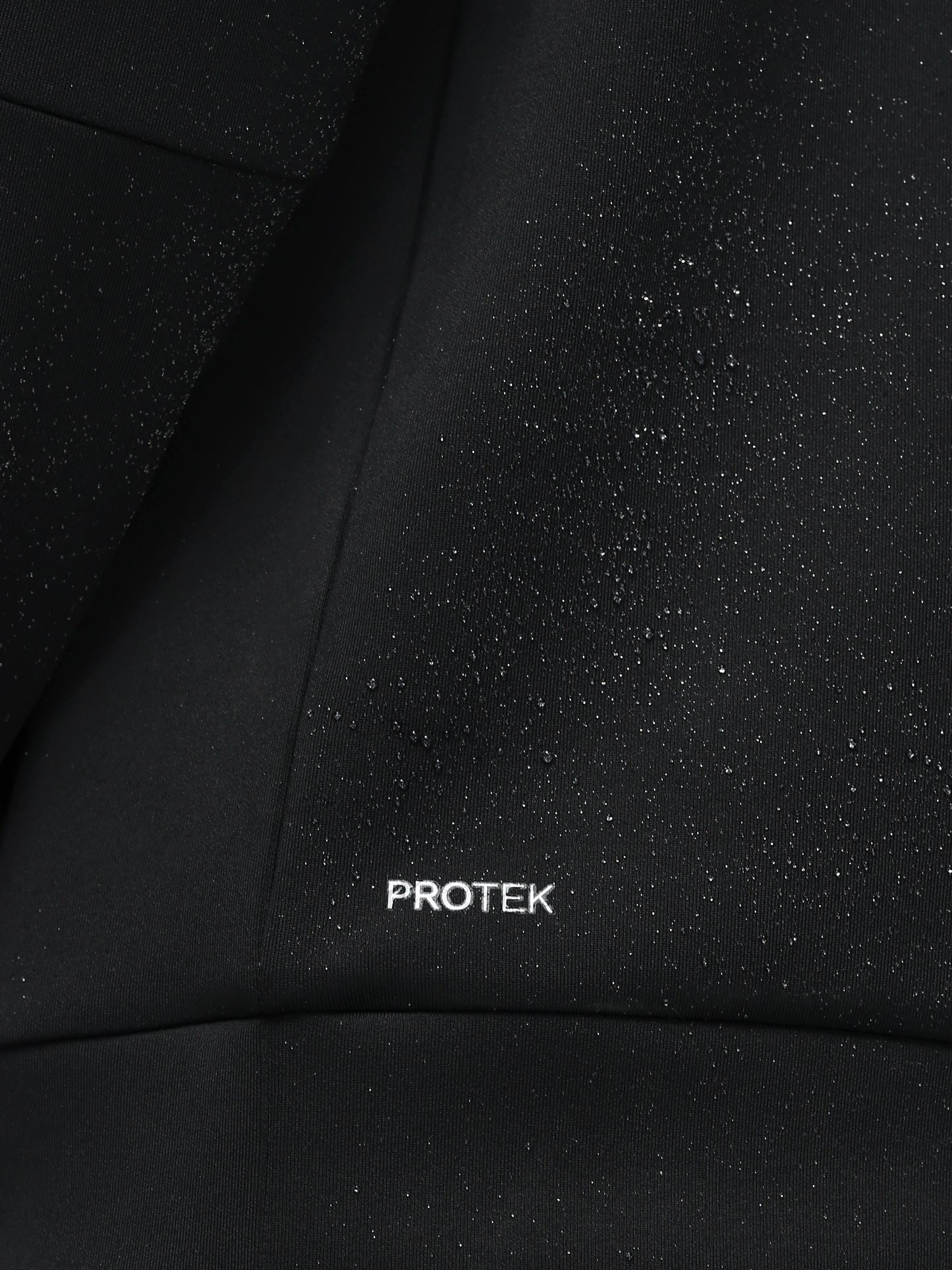 Close-up of black fabric with 'PROTEK' branding.