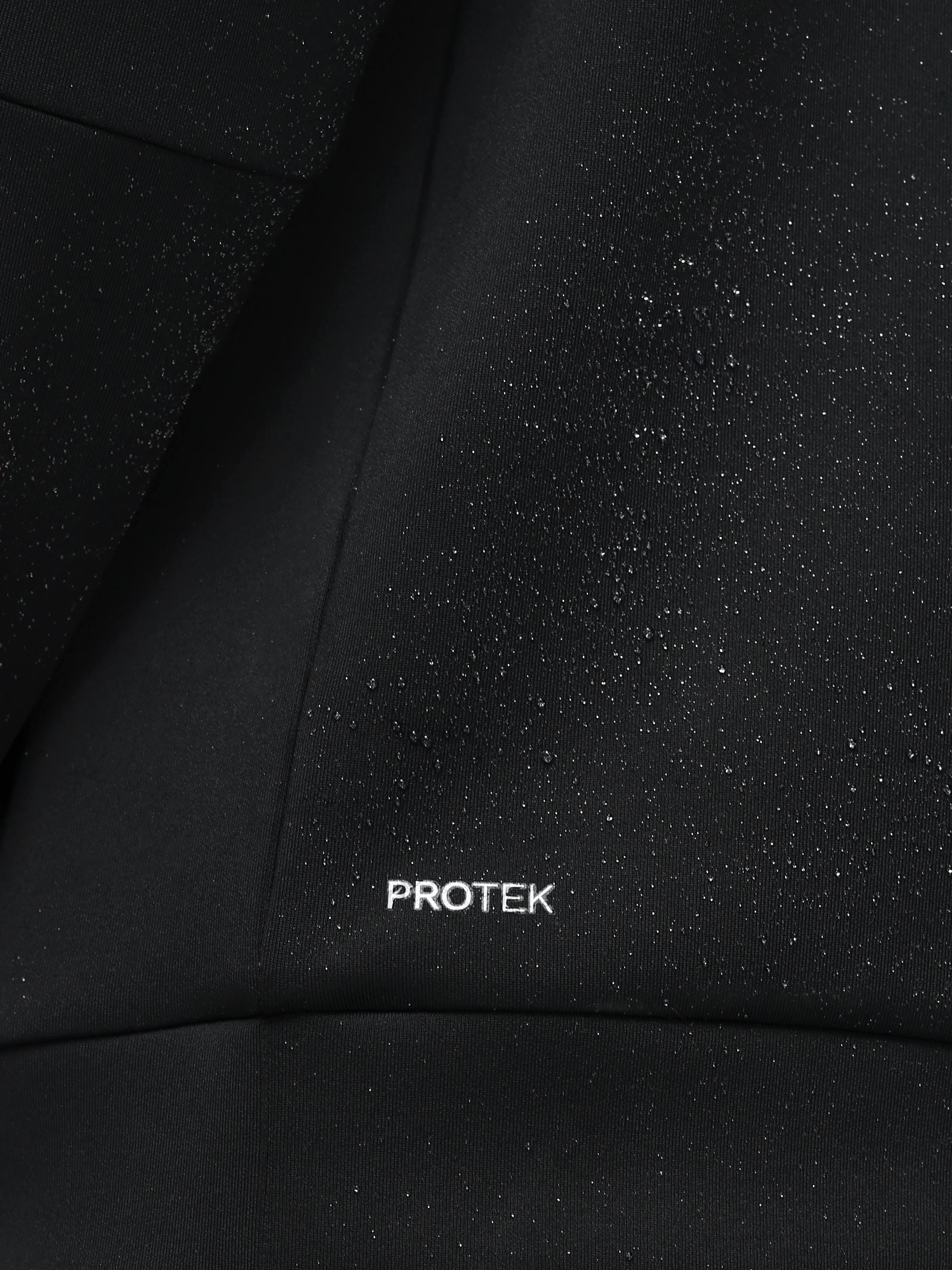 Close-up of black fabric with 'PROTEK' branding.