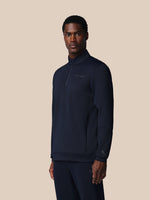 Man wearing a navy blue quarter-zip sweatshirt on a beige background