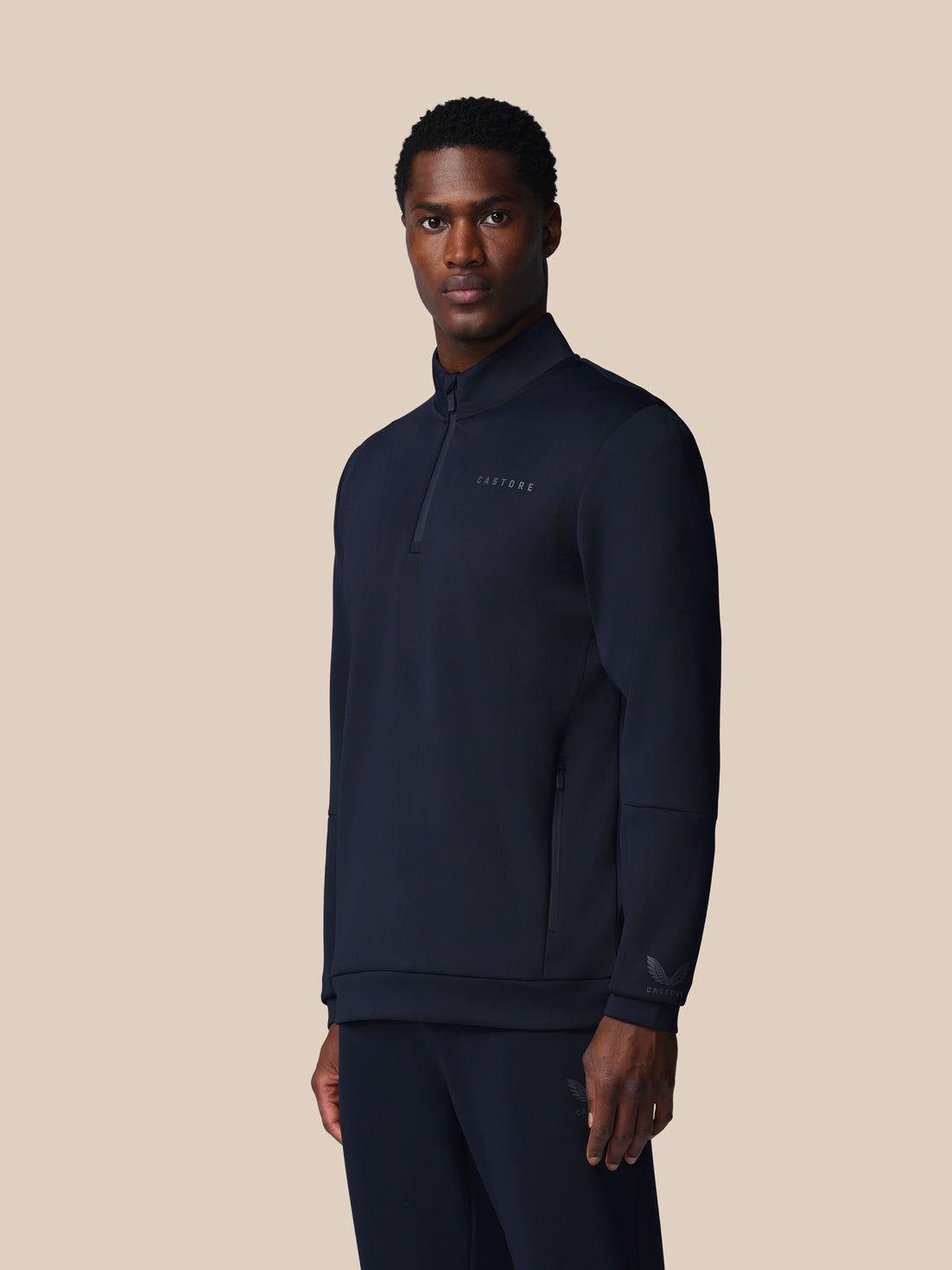 Man wearing a navy blue quarter-zip sweatshirt on a beige background