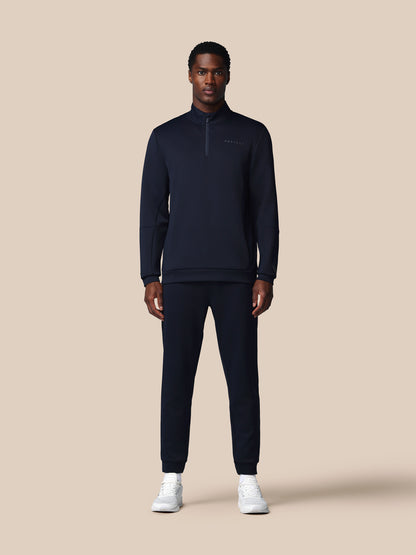 Man wearing a dark navy tracksuit on a beige background
