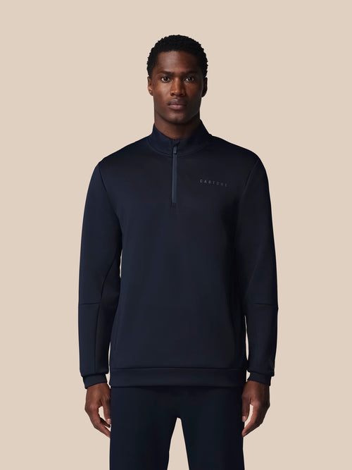 Man wearing a black quarter-zip sweatshirt on a beige background