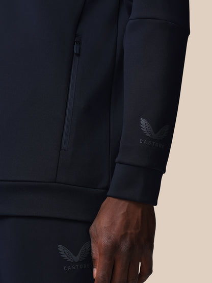 Black jacket with brand logo on sleeve against a beige background