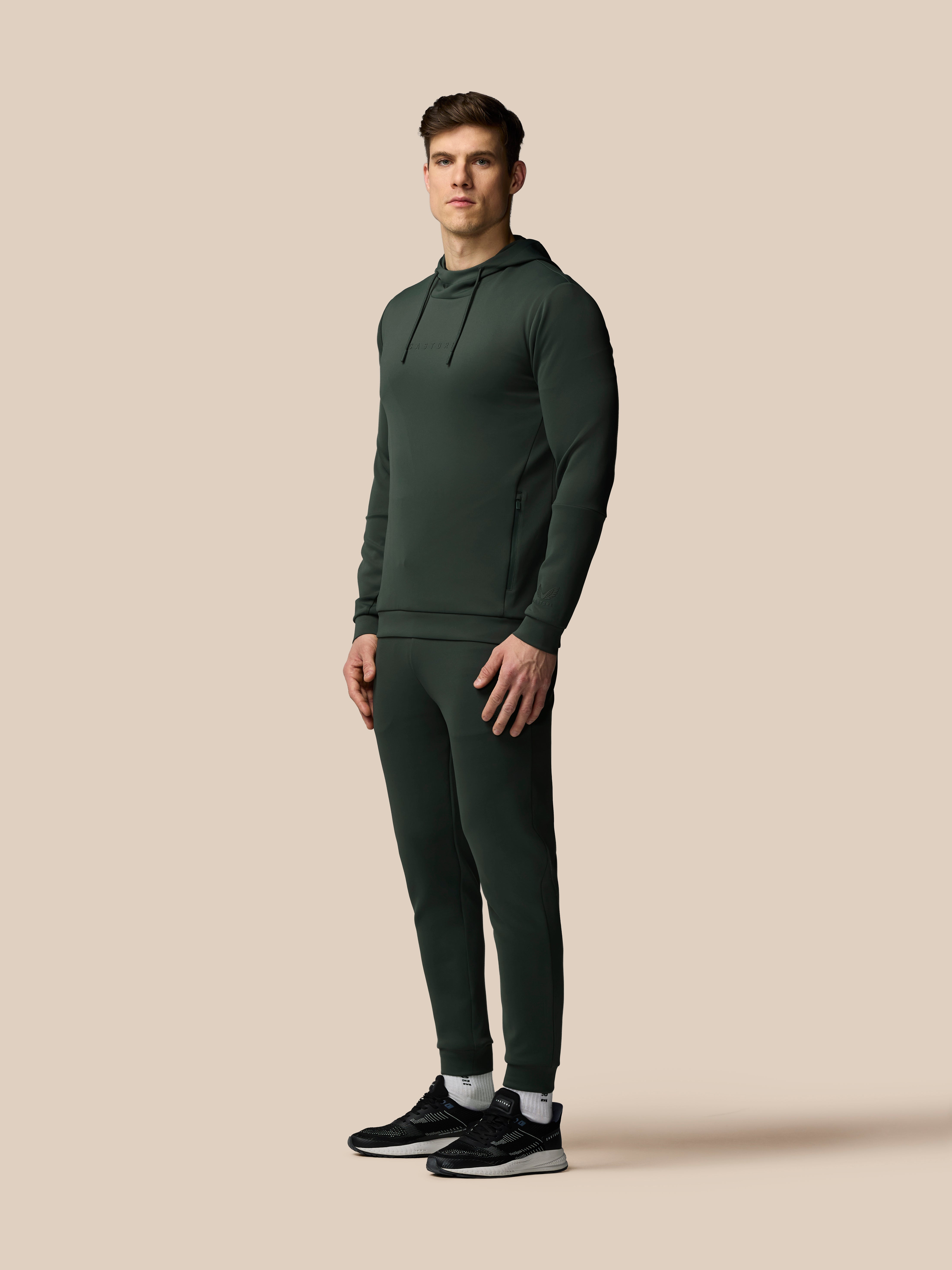 Man wearing a dark green tracksuit on a beige background