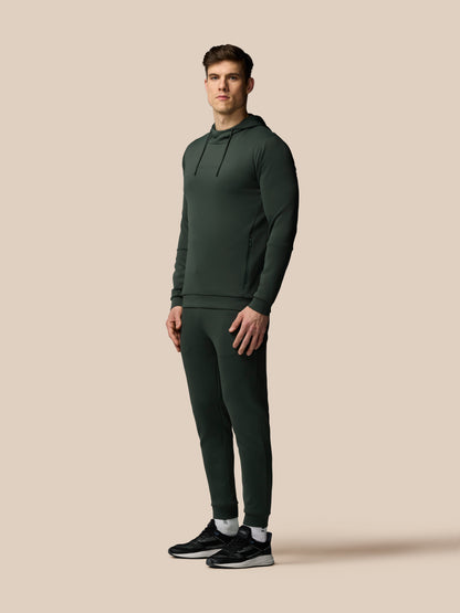 Man wearing a dark green tracksuit on a beige background