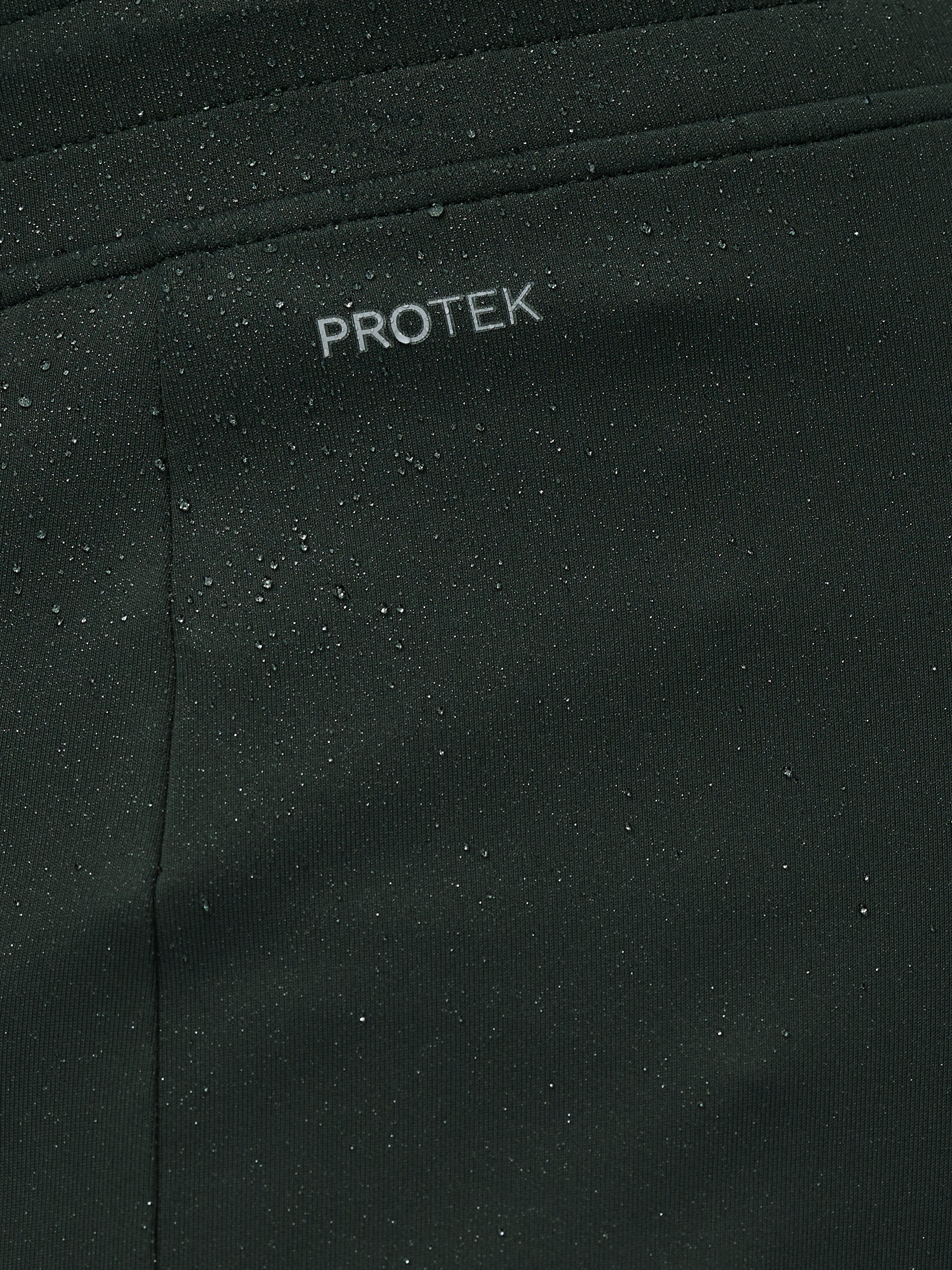 Close-up of black fabric with 'PROTEK' branding.