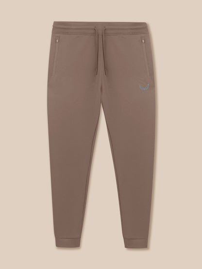Brown jogger pants with a small logo on a beige background