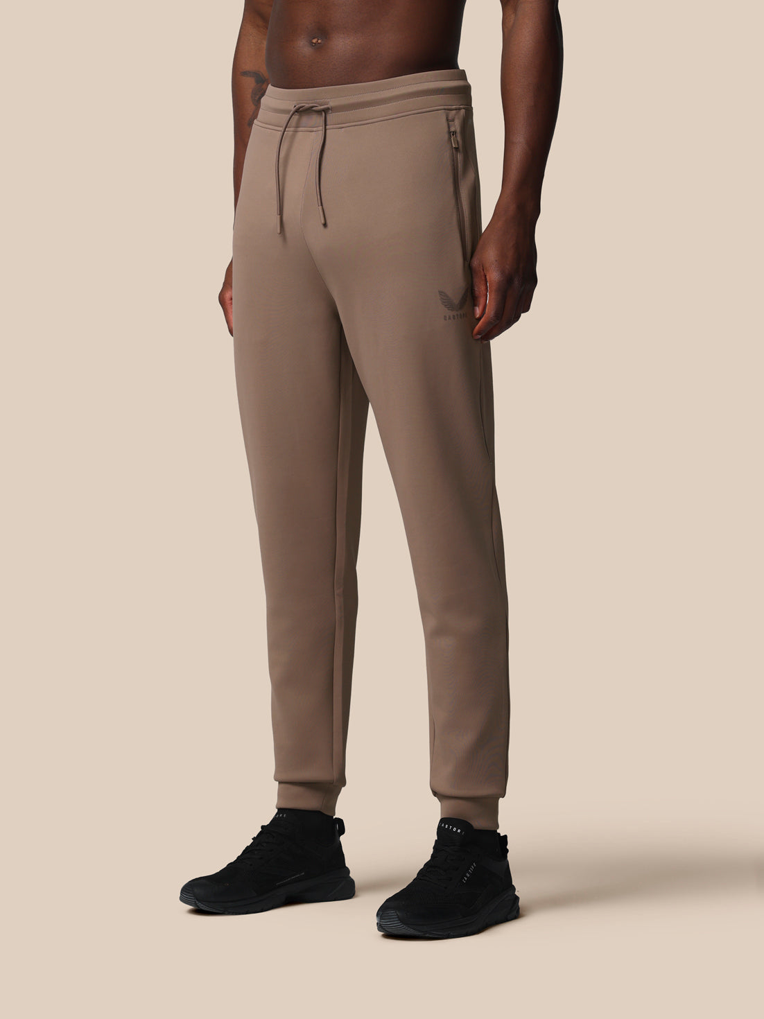 Beige jogger pants worn by a person on a beige background