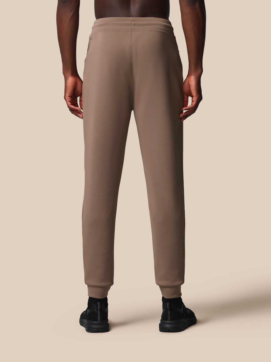Beige sweatpants worn by a person on a beige background