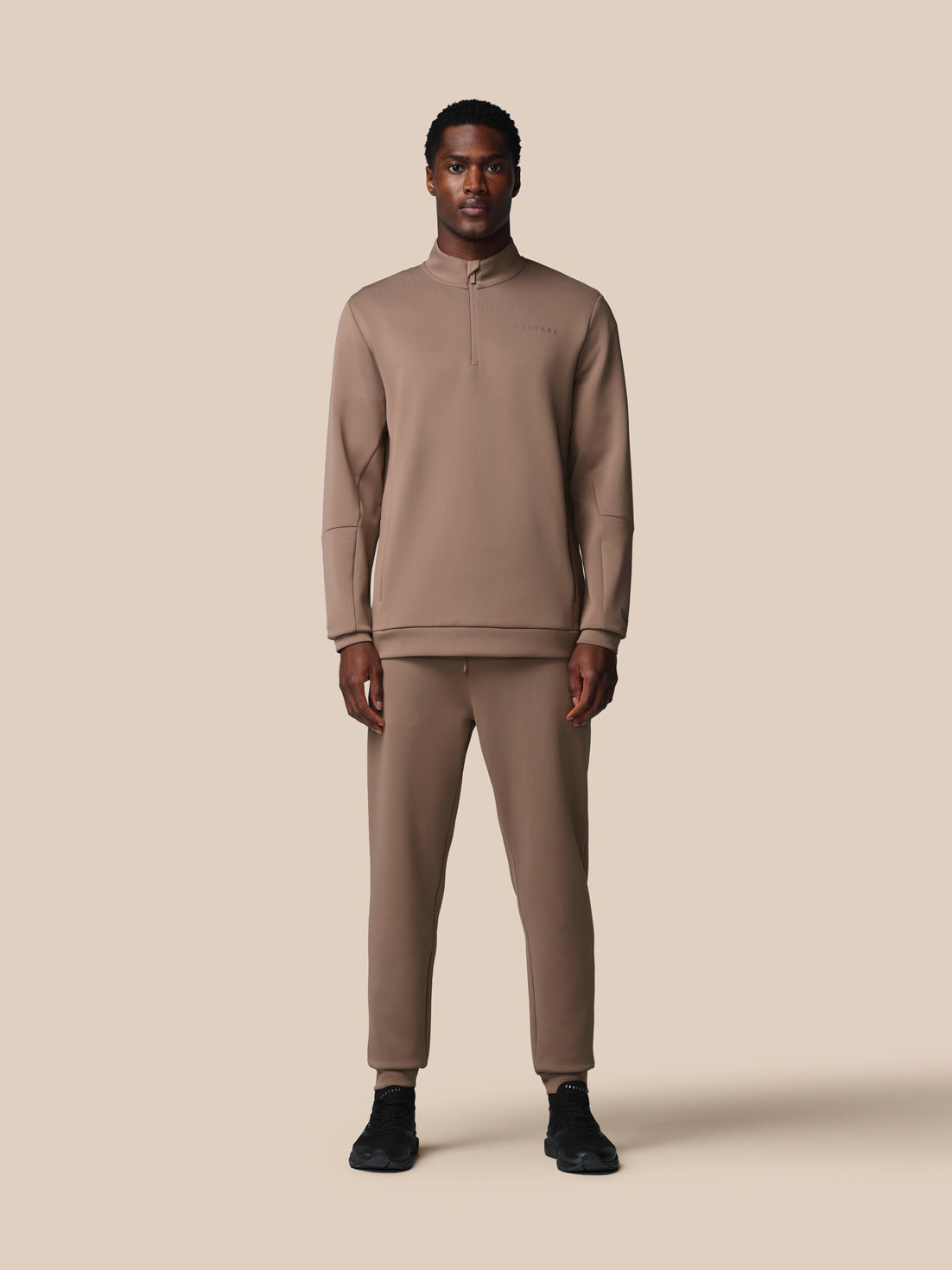 Man wearing a beige tracksuit on a beige background