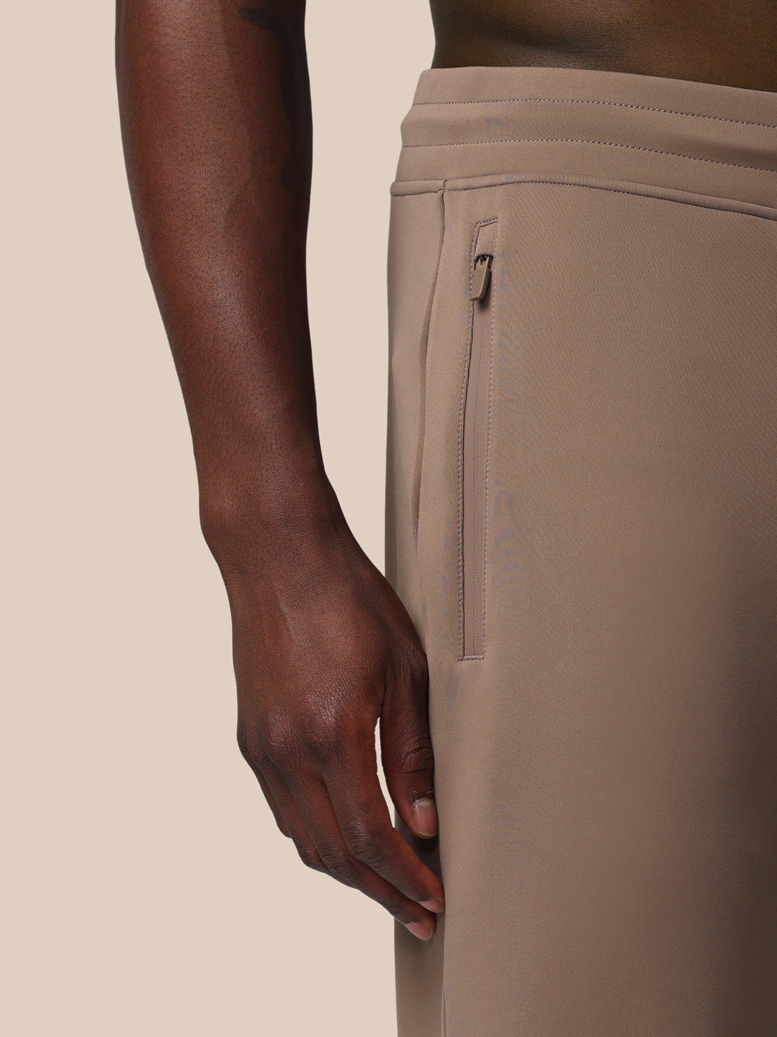 Beige pants with a zipper pocket on a neutral background