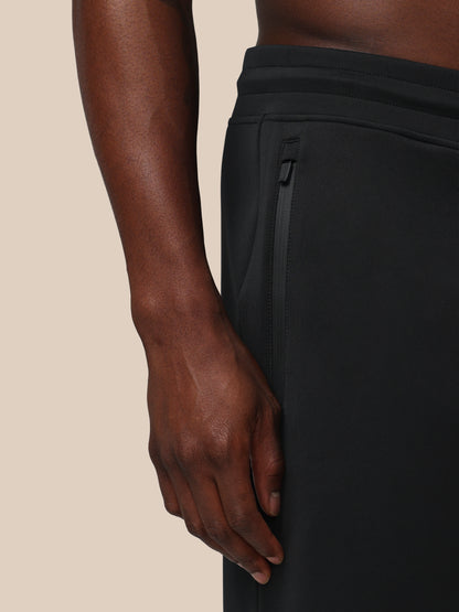 Person wearing black pants with a beige background