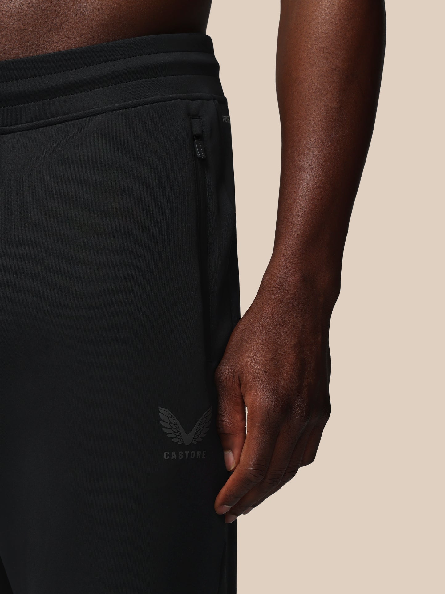 Black athletic pants with a brand logo on a beige background