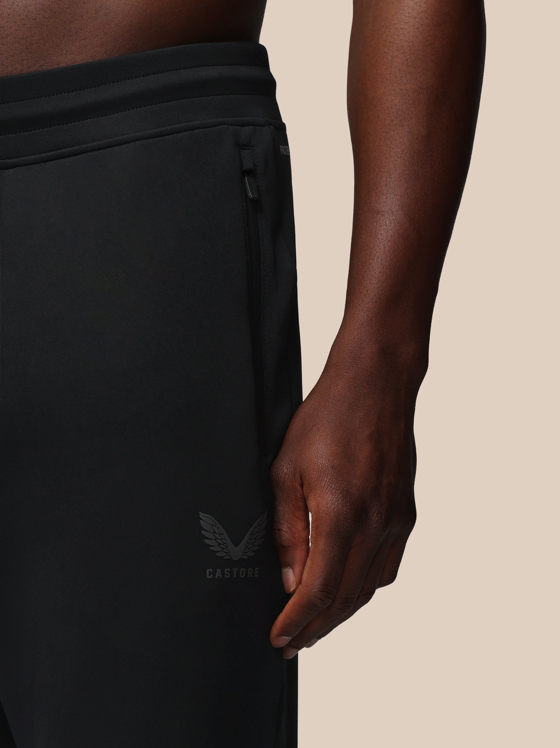Black athletic pants with a brand logo on a beige background