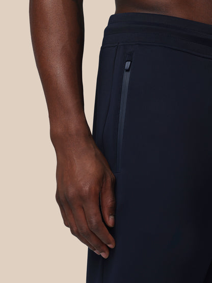 Navy blue athletic pants with a close-up of a hand on a beige background
