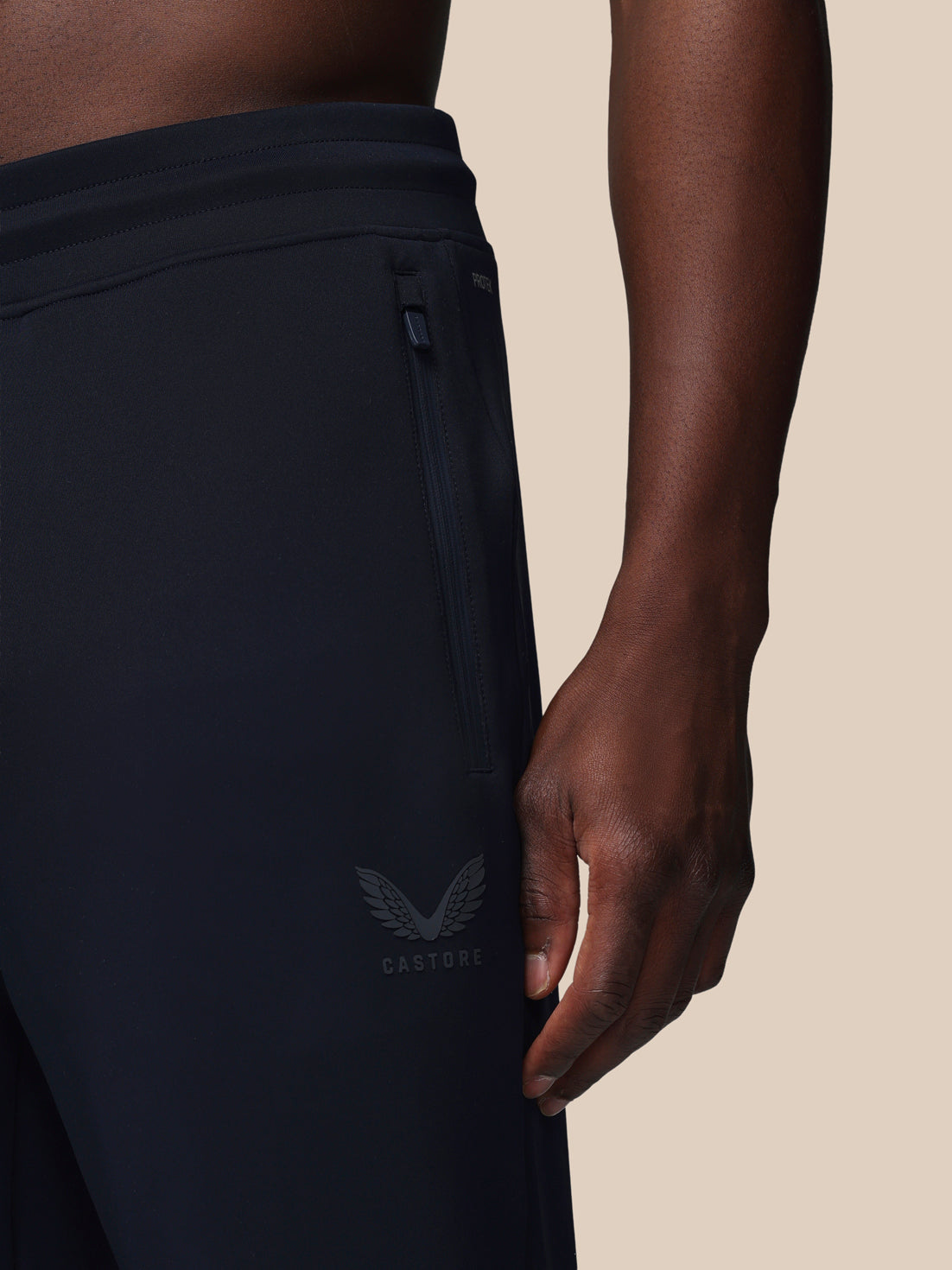 Black athletic pants with a logo on a beige background