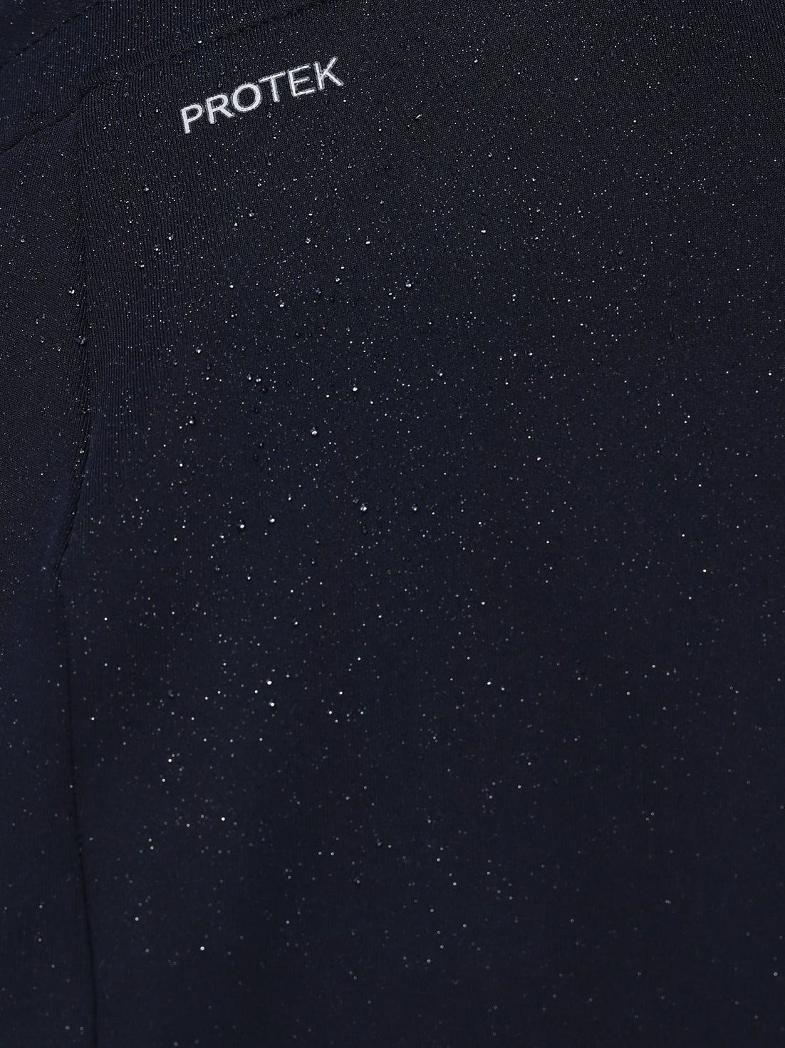 Close-up of a black textured fabric with 'PROTEK' branding.