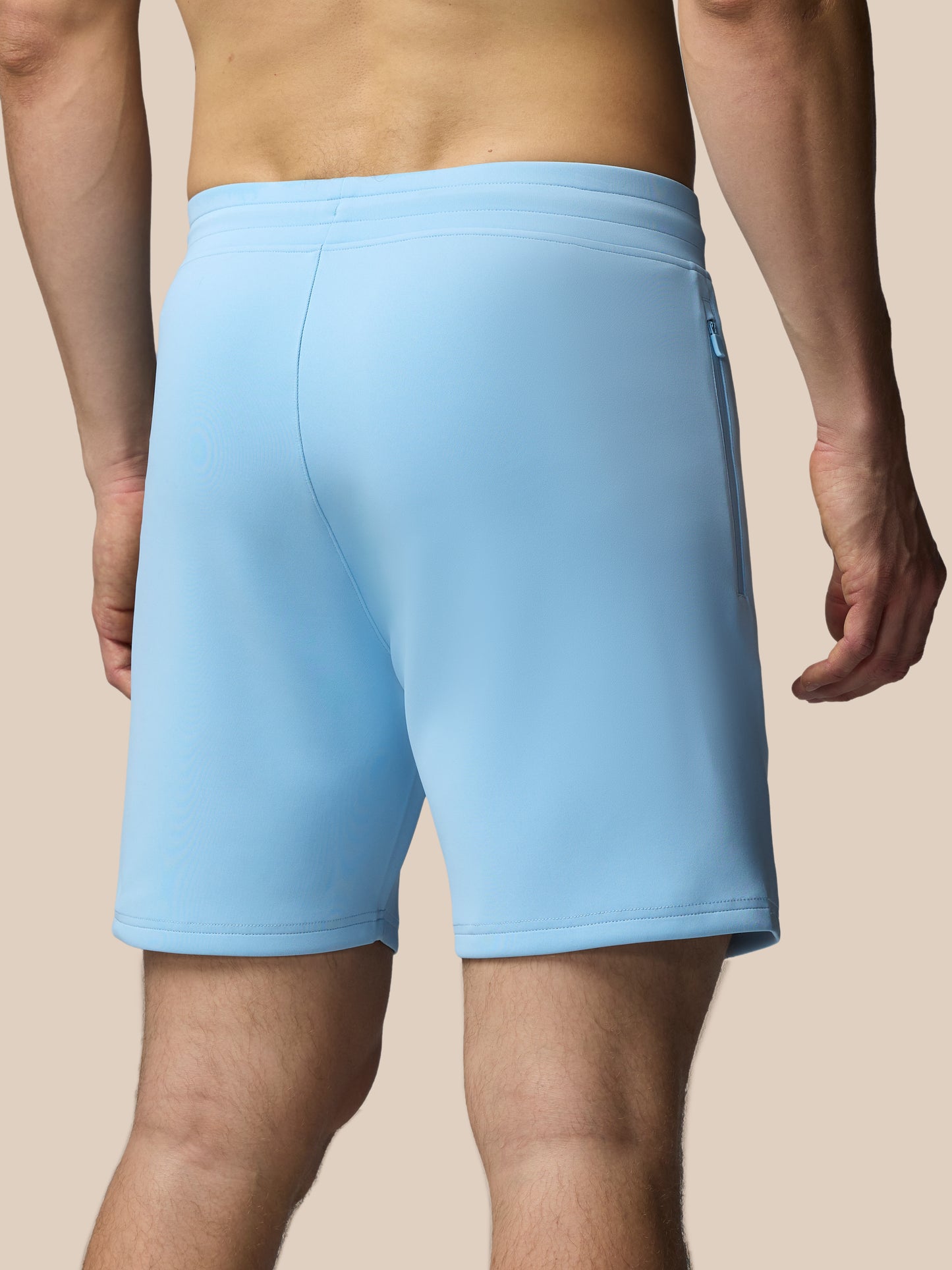 Light blue athletic shorts worn by a person on a beige background