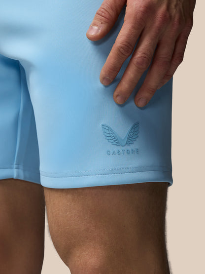 Light blue athletic shorts with a brand logo on a beige background