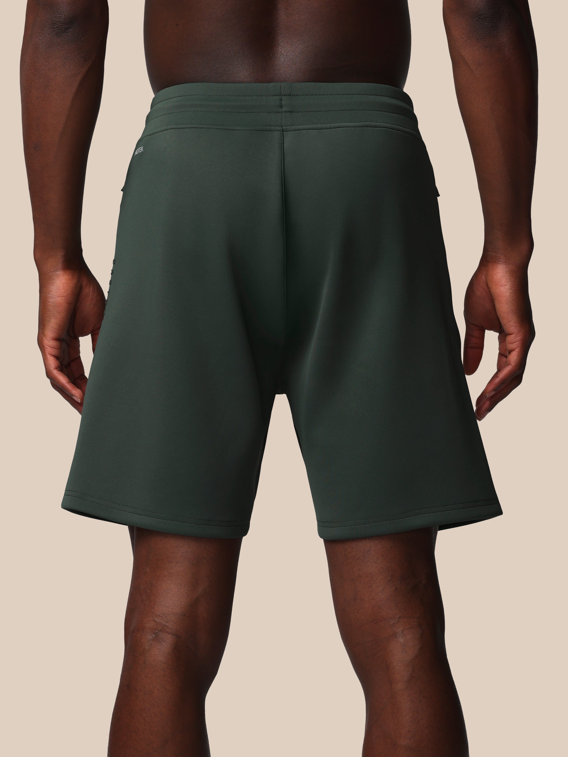 Person wearing dark green shorts on a beige background