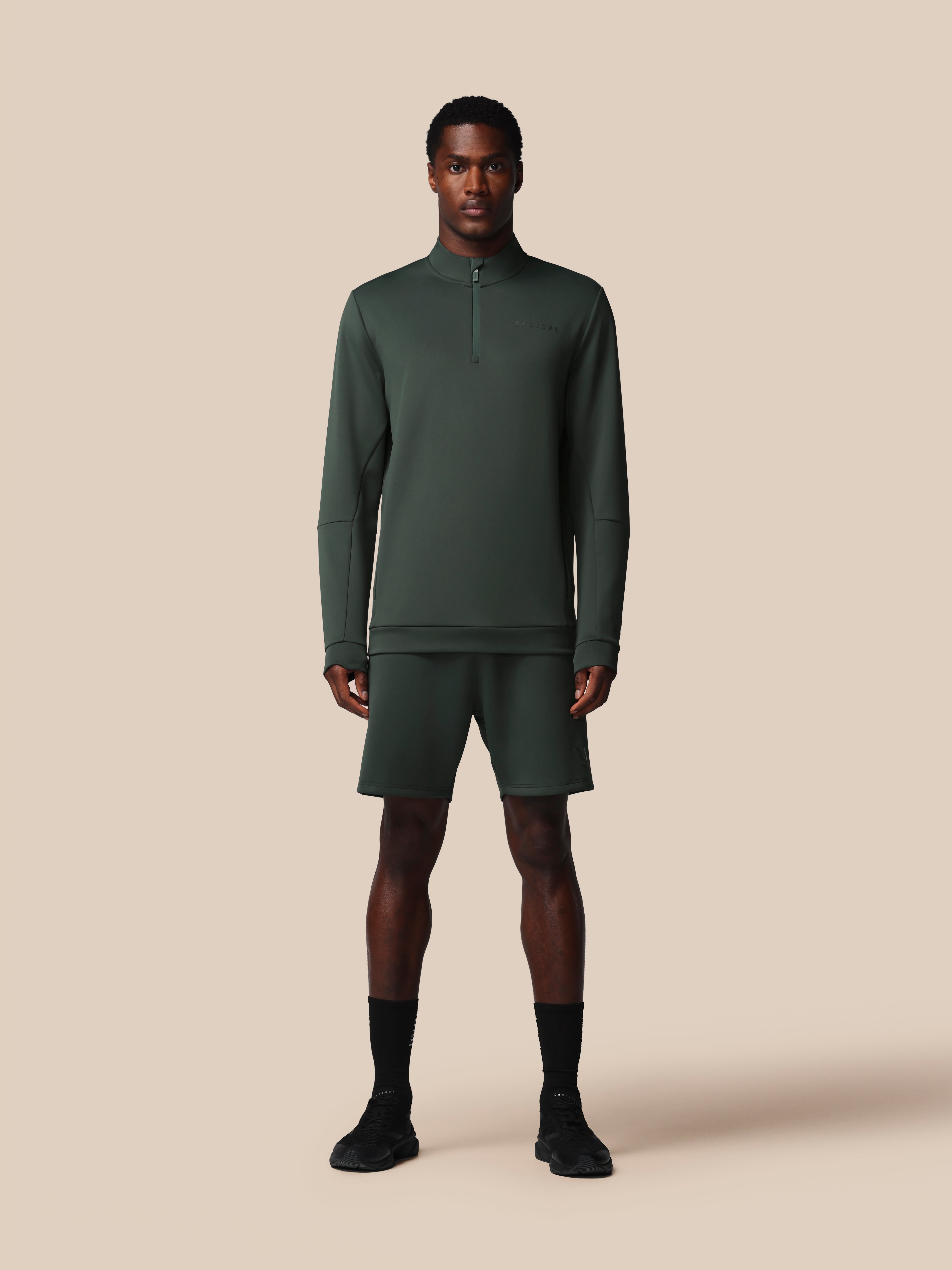 Man wearing a green athletic outfit on a beige background