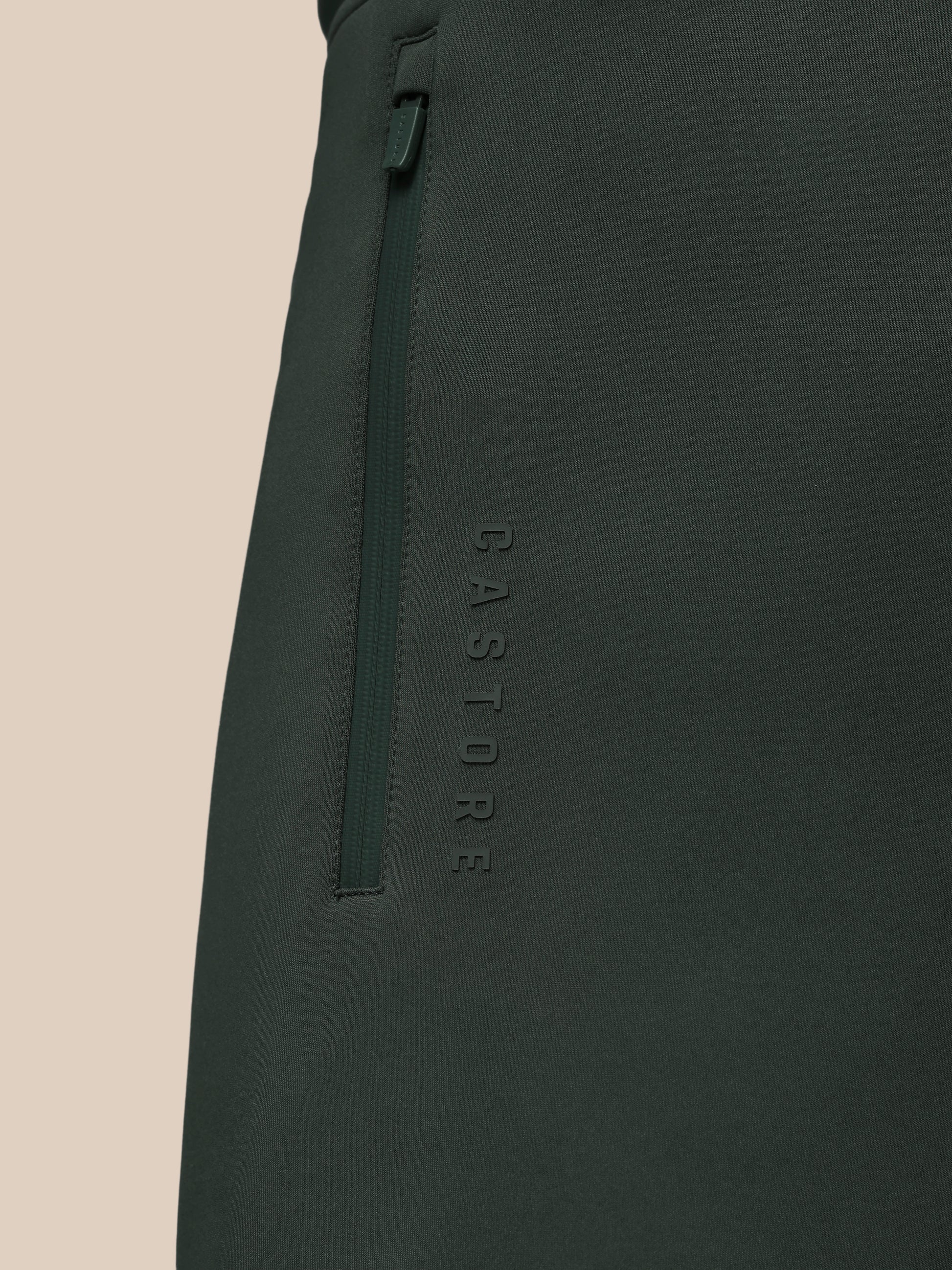 Dark green pants with 'CASTORE' branding on a beige background