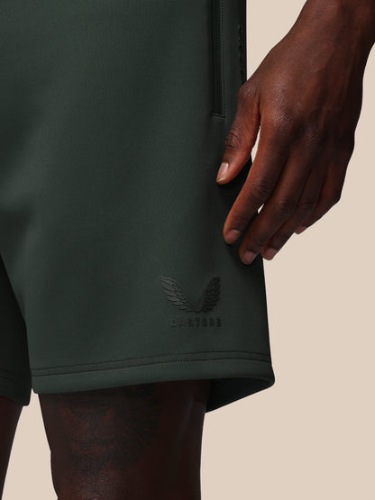Dark green shorts with a brand logo on a beige background