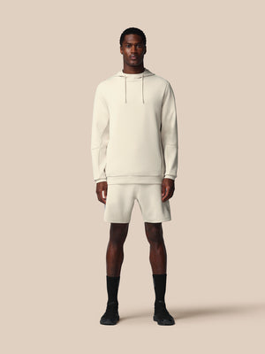 Man wearing a white hoodie and shorts set on a beige background
