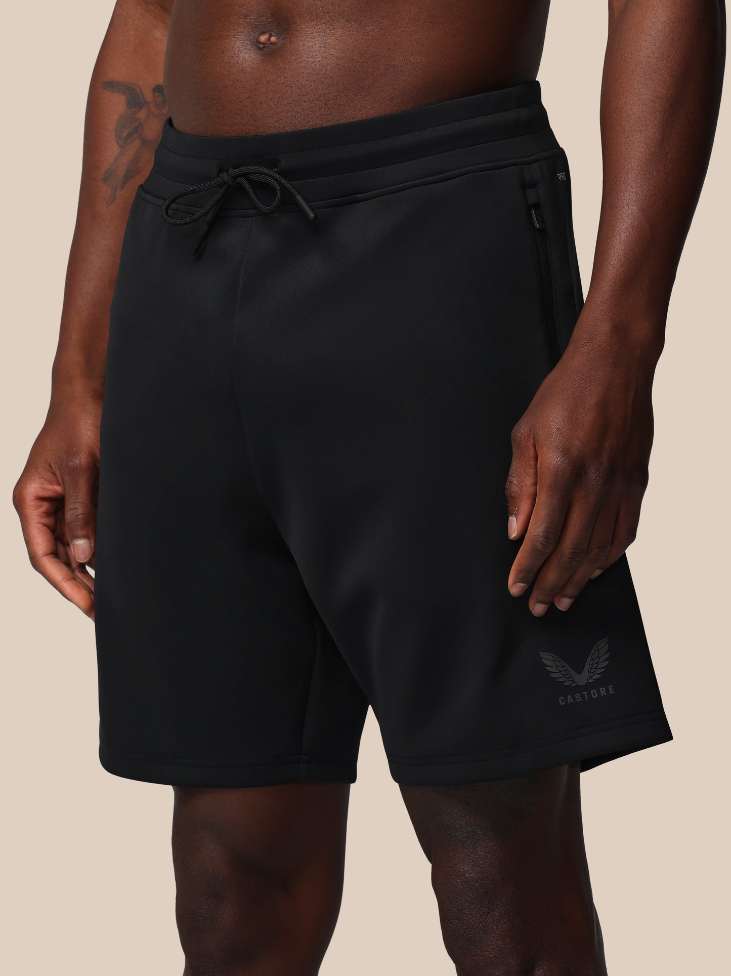 Black shorts worn by a person on a beige background