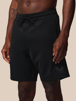 Black shorts worn by a person on a beige background