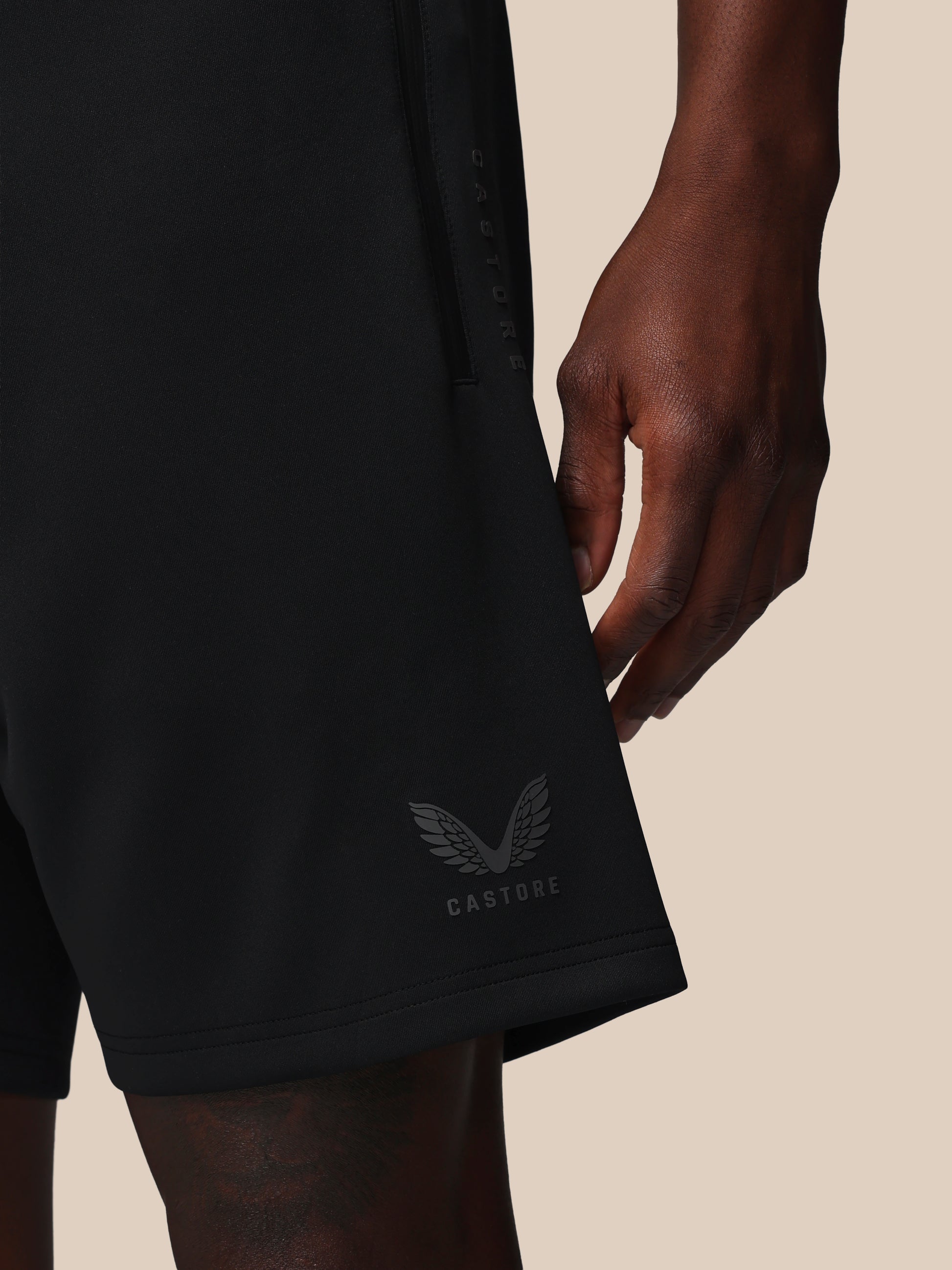 Black shorts with a brand logo on a beige background