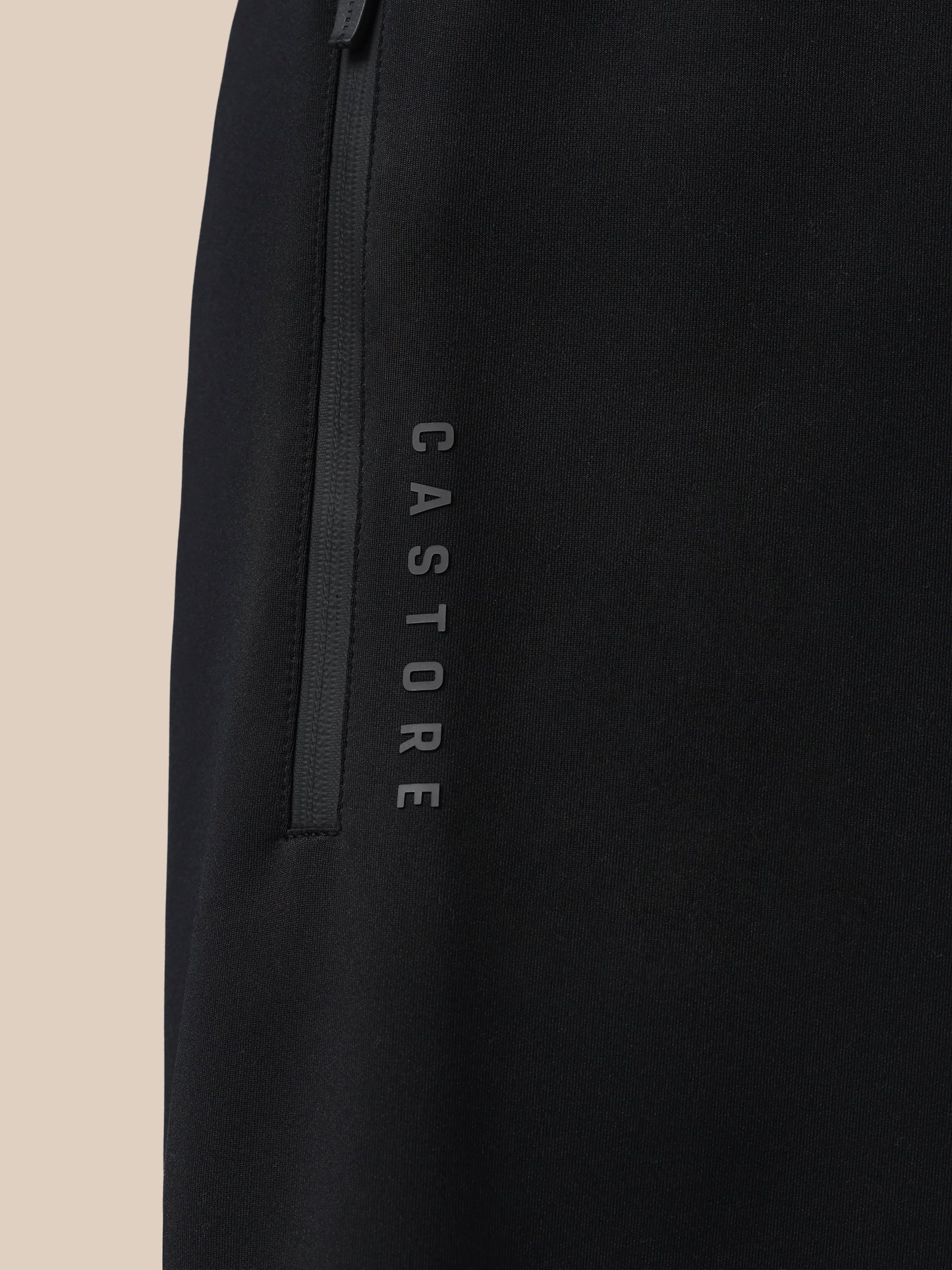 Black jacket with 'Castore' branding on a beige background