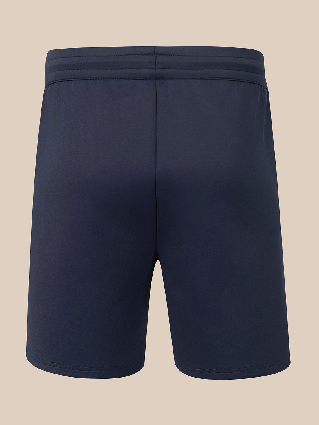 A pair of dark navy athletic shorts shown from the back, featuring a wide elastic waistband, on a solid beige background.