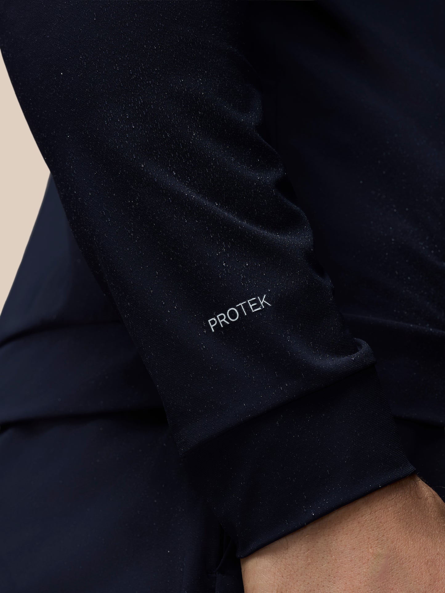 Close-up of a black sleeve with 'PROTEK' branding on a beige background
