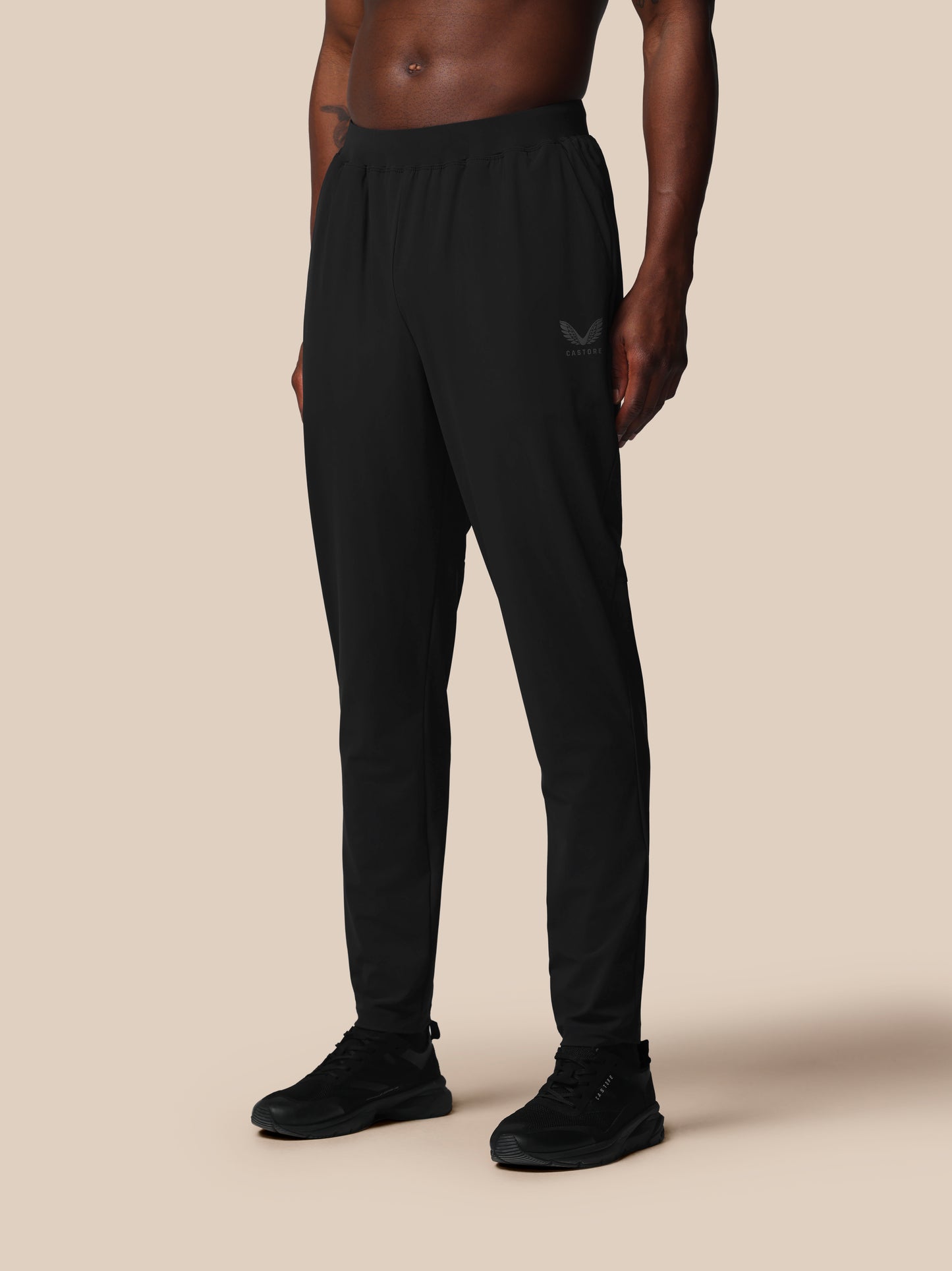 Person wearing black Castore pants on a beige background