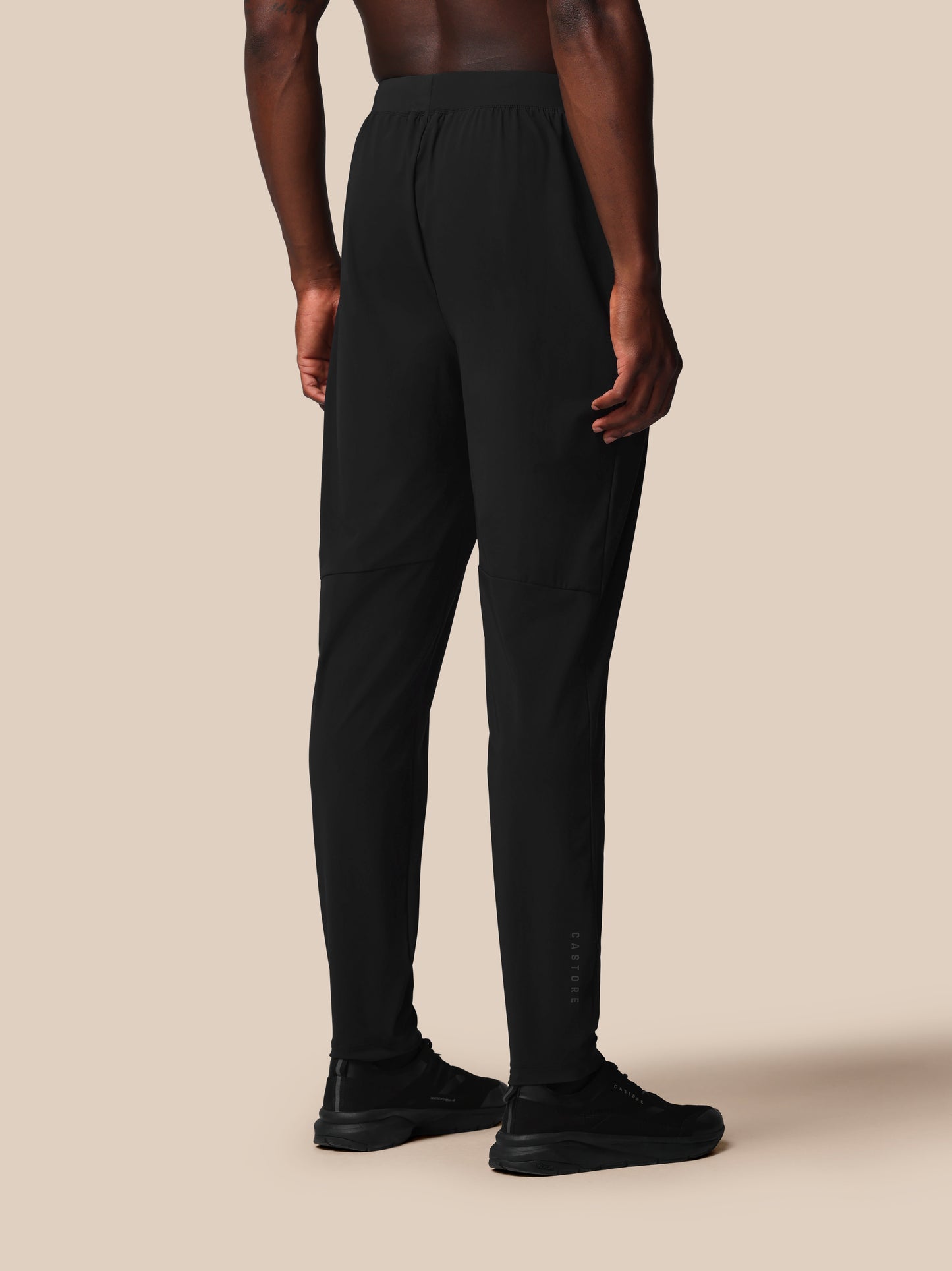 Person wearing black pants on a beige background